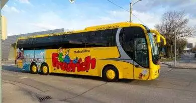 Ein gelber Bus fährt die Straße entlang, Anbieter Busreisen.