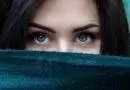Eine Frau mit grünen Augen schaut aus einem Schal hervor.