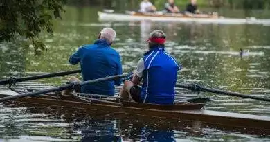 Zwei Männer rudern in einem Ruderboot auf einem See.