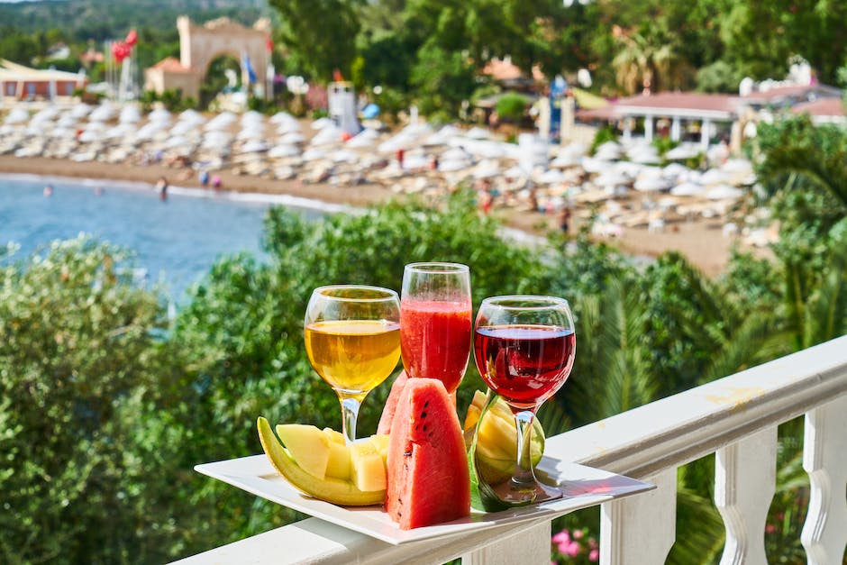 Zwei Gläser Wassermelonensaft und Obst auf einem Balkon mit Blick auf den Strand.